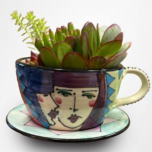 Denise Ford hand painted cup and saucer with succulents. Cup has a male and female face on the front
