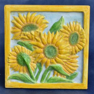 Ann Iverson's garden tile of cast concrete depicting yellow sunflowers, green leaves and stems