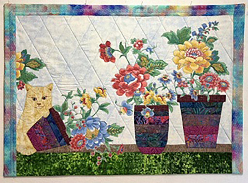 Jennifer Baker's Fused and pieced cotton fabrics, quilted with "ready to hang" back sleeve featuring a cat and flowers in pots
