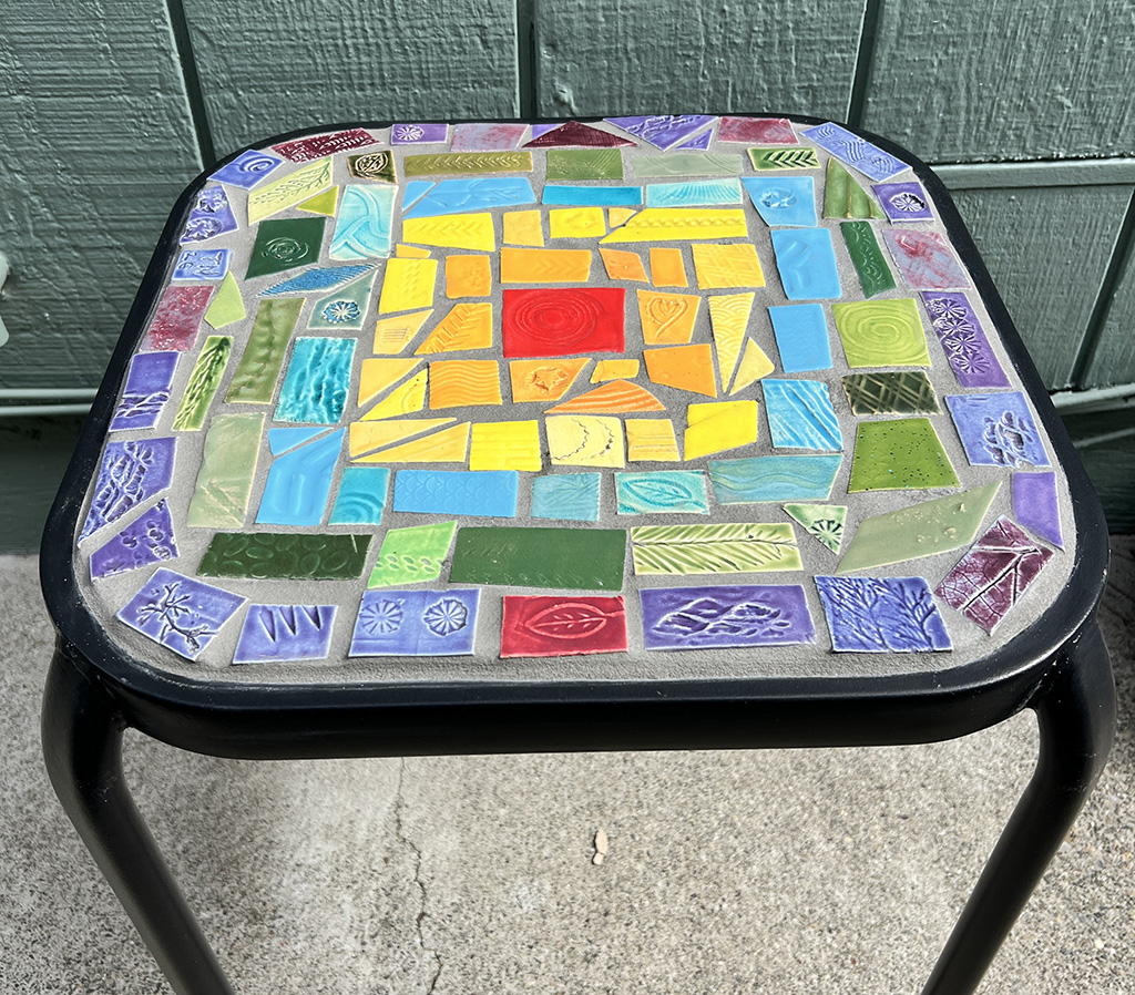Trish Nugent's small black table with artist-made rainbow-colored tile mosaic on top