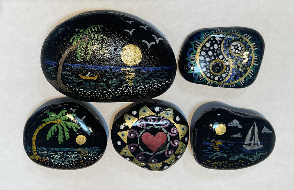 Andra Sanberg's hand-painted black stones. Small scene painted on each one