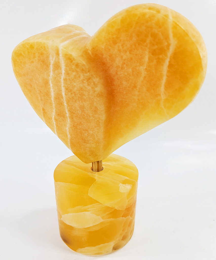 Rene Dayan Whithead's hearts a fire stone sculpture in the shape of a heart made from honeycomb calcite on honeycomb calcite base shades of yellow with veins of white